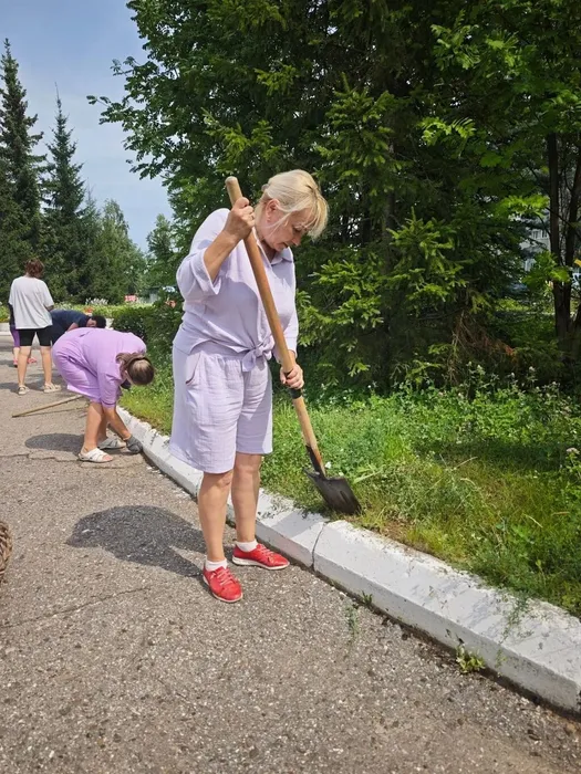 Педагог очищает бордюр от сорняков