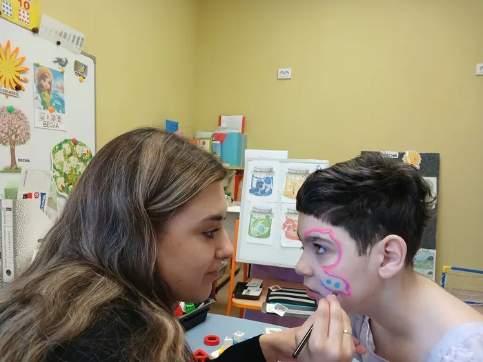 Педагог рисует ребенку аквагрим