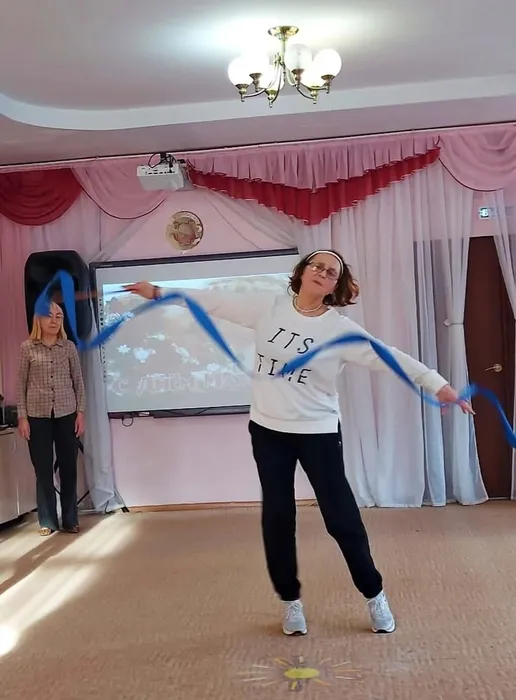 Инструктор по ФИЗО показывает упражнение с лентой