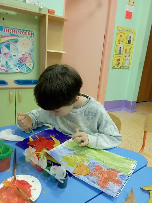 Ребёнок раскрашивает кленовый лист