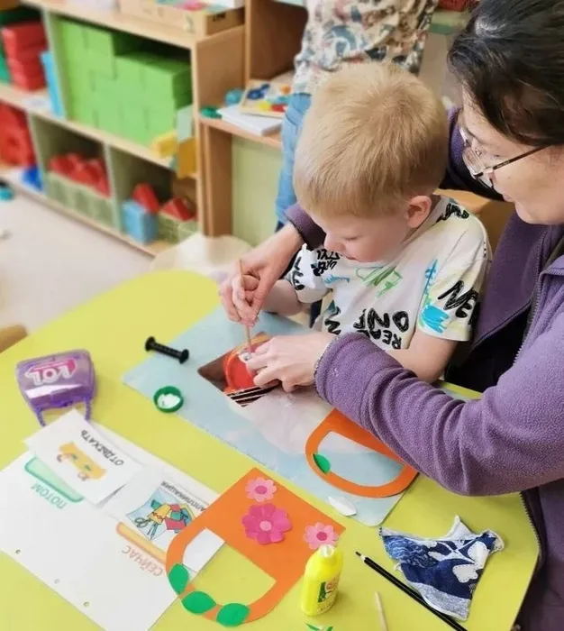 Ребёнок наносит кистью клей на заготовку