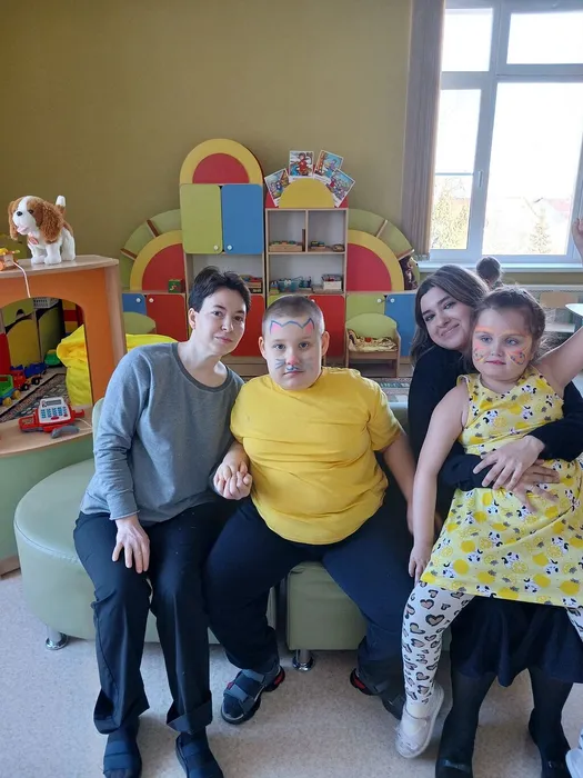 Дети с педагогами сидят на диване в группе