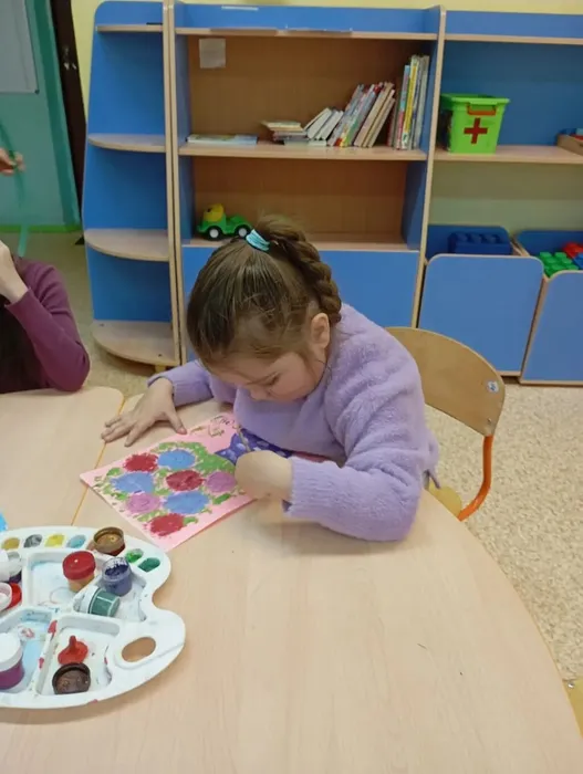 Воспитанница рисует цветы маме
