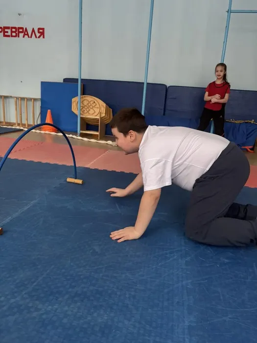 Учащийся 2 И класса пролезает под гимнастическими кольцами