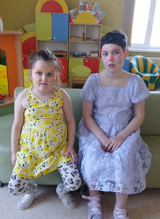 воспитанницы сидят на диване с разрисованными лицами техника Аквагрим