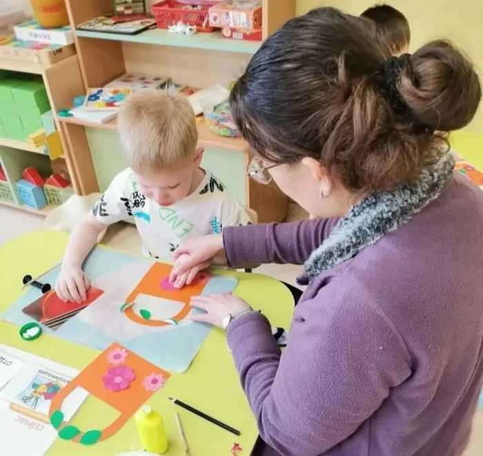 Ребёнок приклеивает зелёный листик