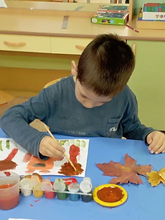 Ребёнок изображает на дереве листья