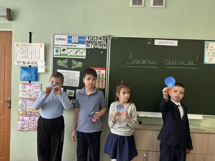 Ребята 2 «И» класса фотографируются с символом  праздника - синими лампочками