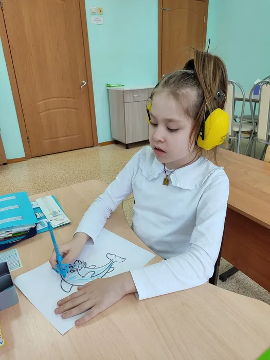 Ученица 1С раскрашивает синим карандашом дельфина