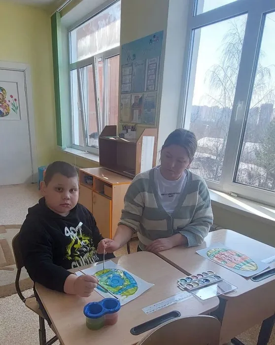 Ученик и педагог  раскрашивают пасхальные яйца