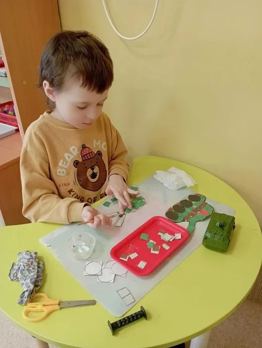 Ребёнок наклеивает зелёный квадрат