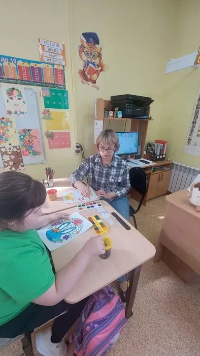 Учитель и ученица раскрашивают пасхальные яйца