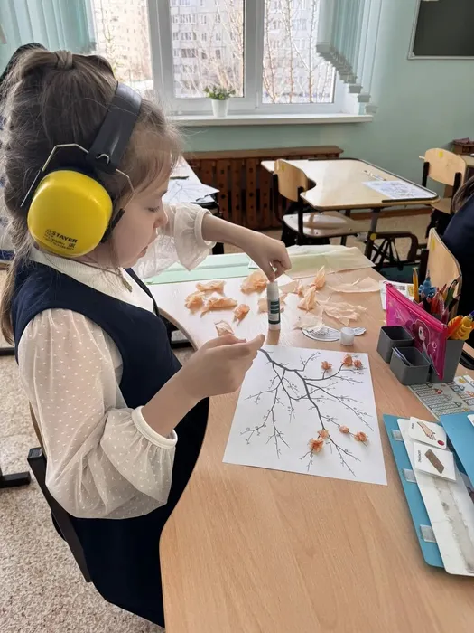 ученица клеит бумагу на заготовку дерева