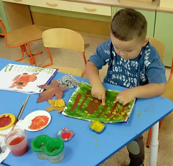 Ребёнок рисует листья пальчиком