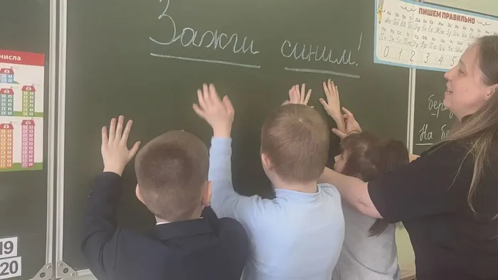 Учащиеся ставят отпечатки ладоней на доску